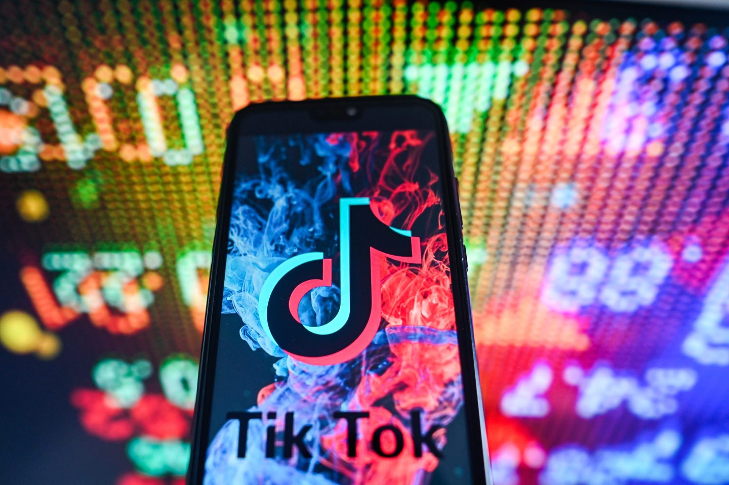 In this photo illustration a TikTok logo is displayed on a smartphone with stock market percentages in the background.
